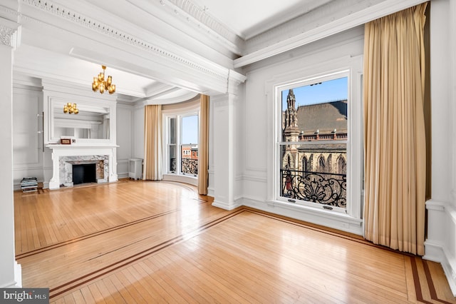 unfurnished living room featuring a fireplace, a chandelier, crown molding, and light hardwood / wood-style flooring