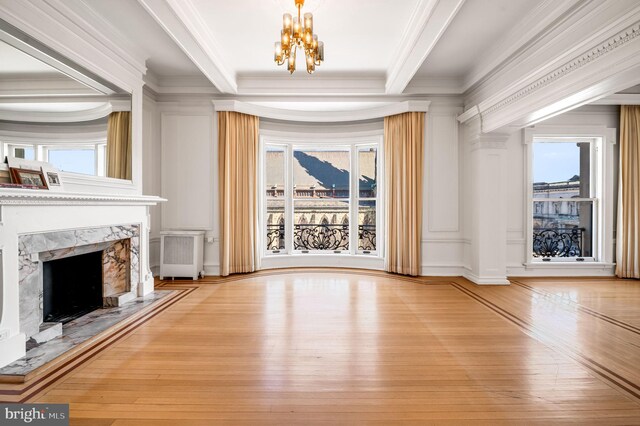 unfurnished living room with light wood-type flooring, a fireplace, a notable chandelier, and ornamental molding