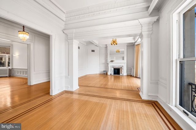 hall featuring a decorative wall, a notable chandelier, wood-type flooring, and ornamental molding