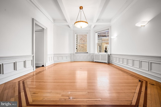 unfurnished dining area with hardwood / wood-style floors, radiator, a wainscoted wall, coffered ceiling, and beamed ceiling