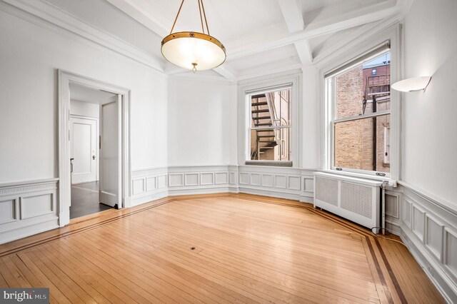 unfurnished room featuring beamed ceiling, radiator, crown molding, and light hardwood / wood-style flooring