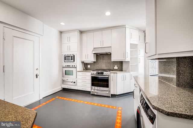 kitchen featuring under cabinet range hood, backsplash, white cabinetry, stainless steel appliances, and washer / dryer