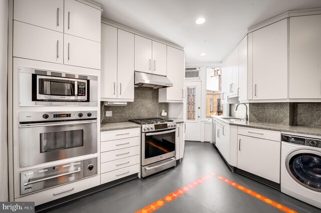 kitchen featuring appliances with stainless steel finishes, white cabinetry, sink, washer / clothes dryer, and decorative backsplash