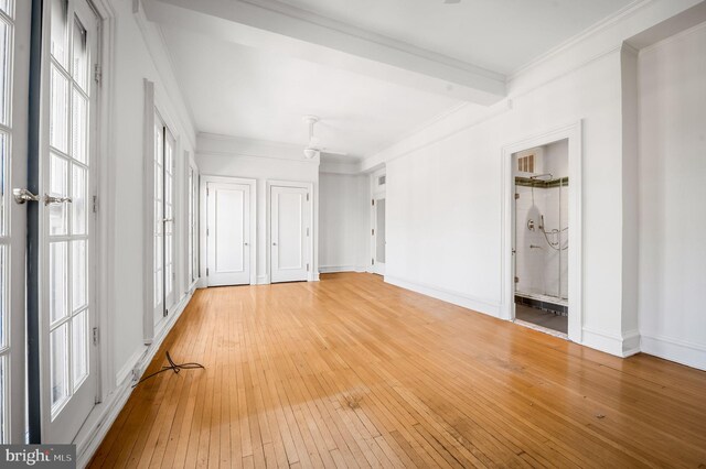 spare room featuring hardwood / wood-style flooring, plenty of natural light, beam ceiling, and ornamental molding