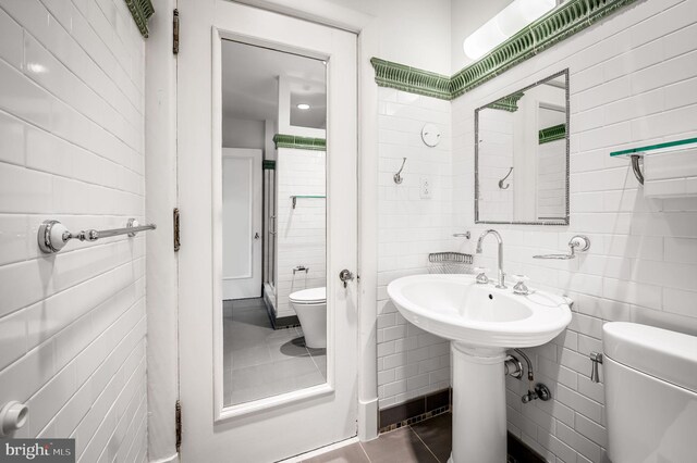 bathroom with tile walls, toilet, and tile patterned floors