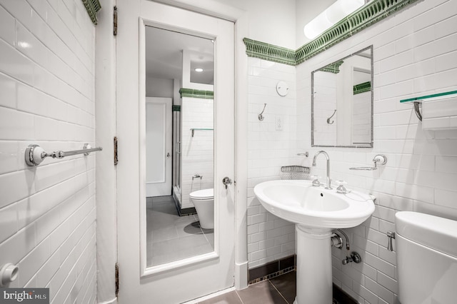 bathroom featuring toilet, tile walls, and tile patterned flooring