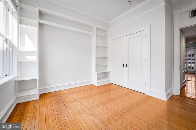 unfurnished bedroom featuring ornamental molding, wood-type flooring, and a closet