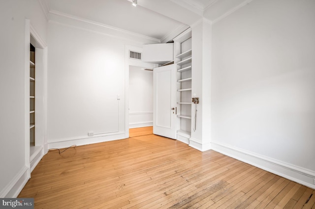 unfurnished bedroom featuring visible vents, wood-type flooring, baseboards, and ornamental molding