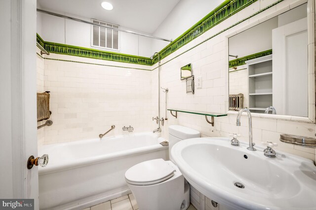 full bathroom with tile walls, toilet, sink, and tiled shower / bath