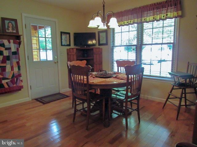 dining space featuring wood-type flooring and an inviting chandelier