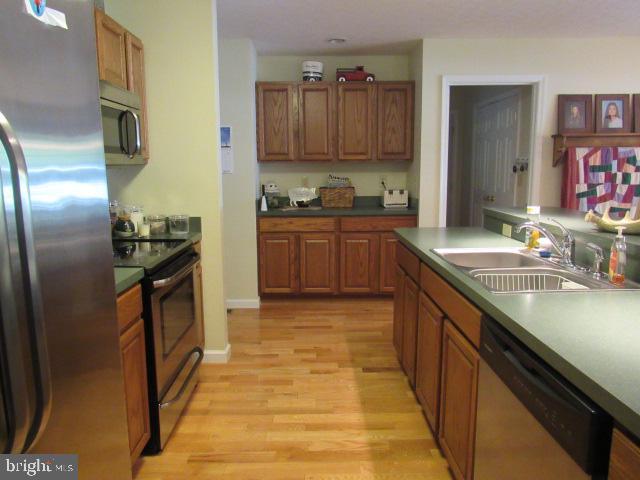 kitchen with stainless steel appliances, sink, and light hardwood / wood-style floors