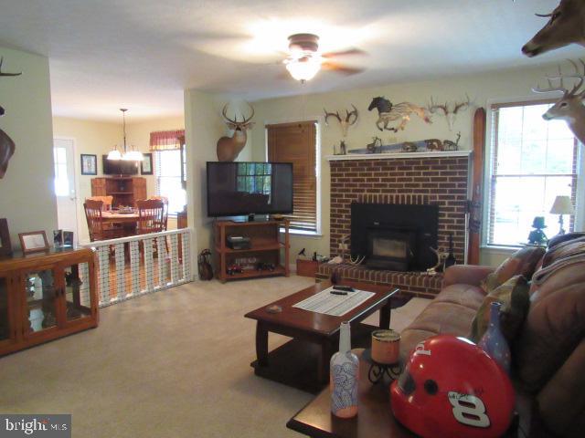 carpeted living room with a fireplace and ceiling fan