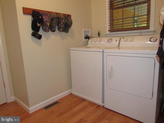 clothes washing area featuring light hardwood / wood-style flooring and washer and clothes dryer