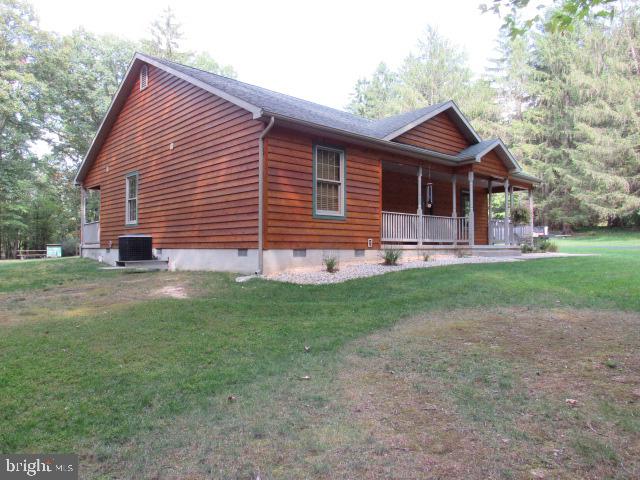 view of side of property featuring cooling unit, a lawn, and a porch