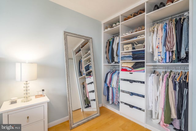 walk in closet with light hardwood / wood-style flooring