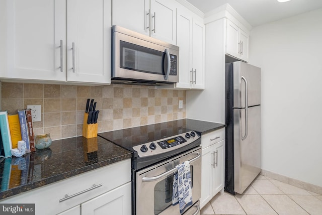 kitchen with appliances with stainless steel finishes, decorative backsplash, white cabinetry, and light tile patterned floors