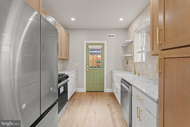 kitchen with light hardwood / wood-style flooring, backsplash, light stone counters, sink, and appliances with stainless steel finishes