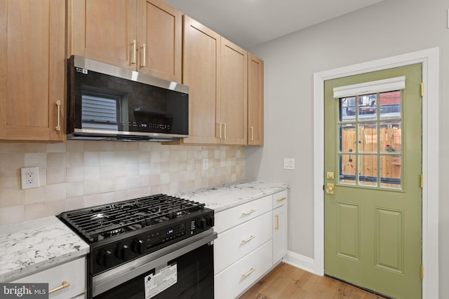 kitchen featuring appliances with stainless steel finishes, light brown cabinetry, decorative backsplash, and light hardwood / wood-style floors