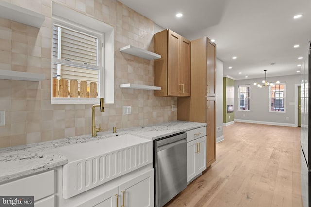 kitchen featuring light hardwood / wood-style flooring, a notable chandelier, stainless steel dishwasher, white cabinetry, and light stone counters