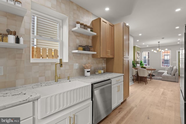 kitchen featuring stainless steel dishwasher, a notable chandelier, light stone countertops, and light wood-type flooring