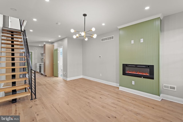 unfurnished living room with a large fireplace, an inviting chandelier, and light hardwood / wood-style floors