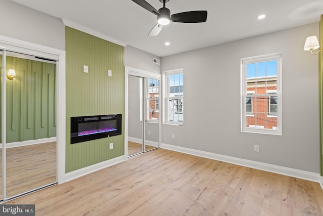 unfurnished bedroom featuring light hardwood / wood-style flooring, ceiling fan, a closet, and multiple windows