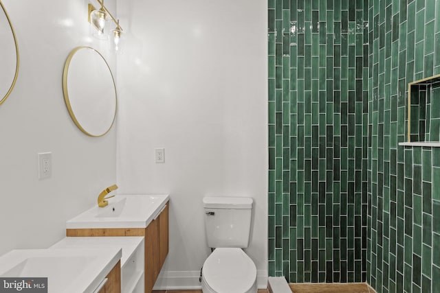 bathroom with vanity, toilet, and a tile shower