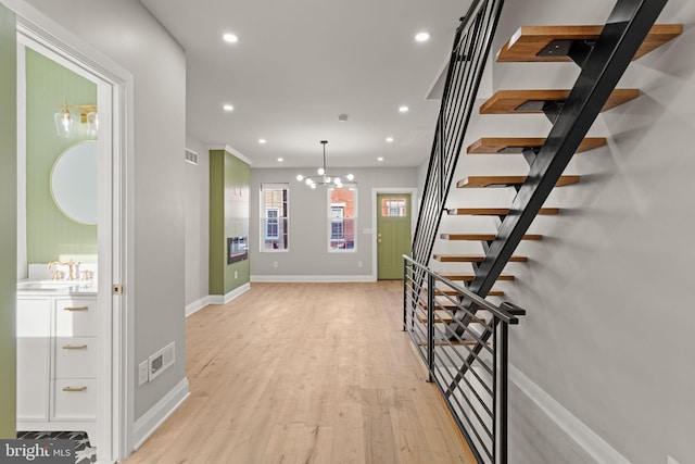 hallway featuring an inviting chandelier, sink, and light wood-type flooring