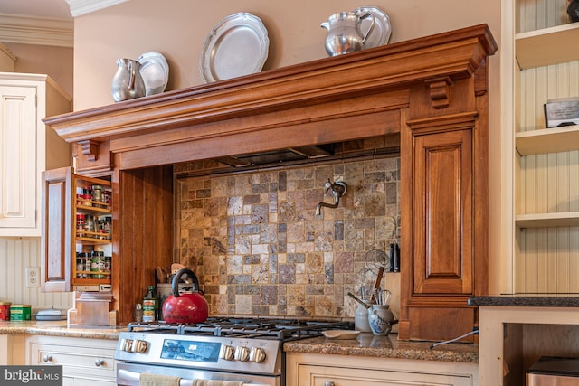 kitchen featuring dark stone counters, stainless steel range oven, crown molding, and tasteful backsplash