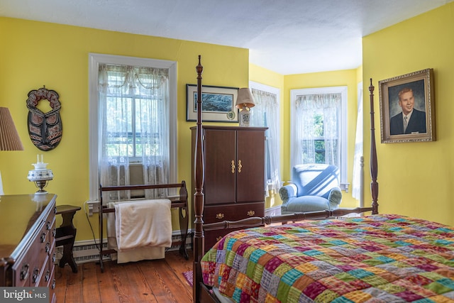 bedroom with baseboard heating and dark hardwood / wood-style flooring