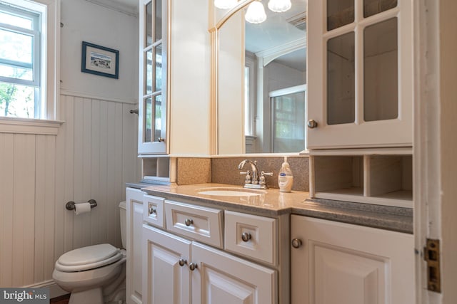 bathroom featuring backsplash, vanity, wooden walls, toilet, and a shower with door