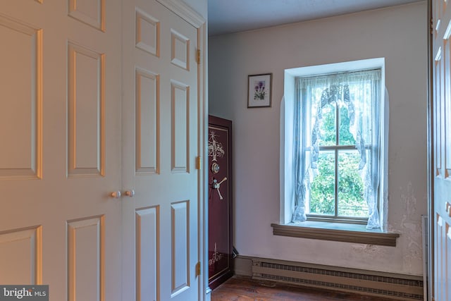 interior space featuring a baseboard heating unit and hardwood / wood-style flooring