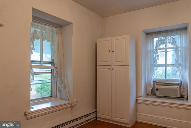 interior space with cooling unit, a baseboard radiator, and dark hardwood / wood-style flooring