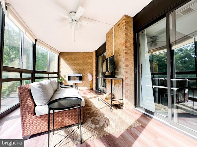 sunroom with a multi sided fireplace and ceiling fan