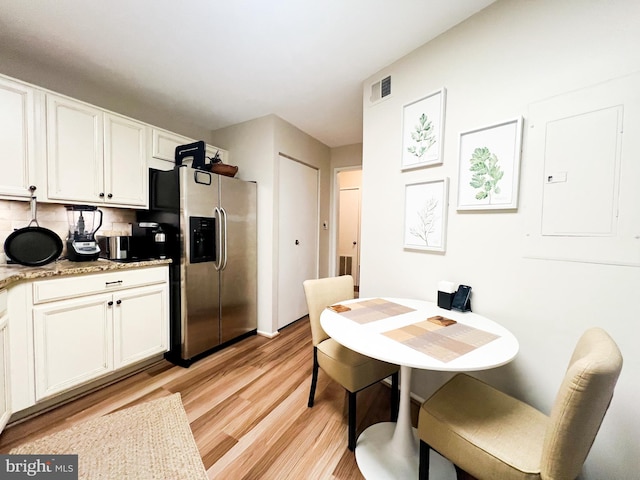 kitchen featuring visible vents, white cabinets, light wood-style floors, and stainless steel refrigerator with ice dispenser