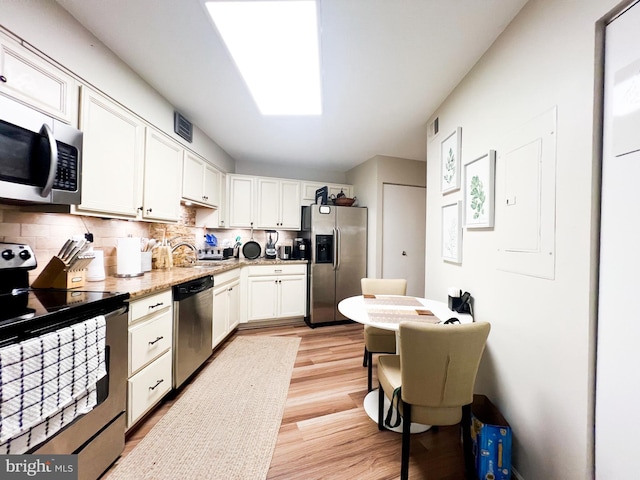 kitchen featuring backsplash, white cabinets, appliances with stainless steel finishes, and light wood-type flooring