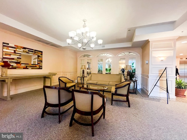 carpeted dining area with a tray ceiling, a wainscoted wall, and a decorative wall