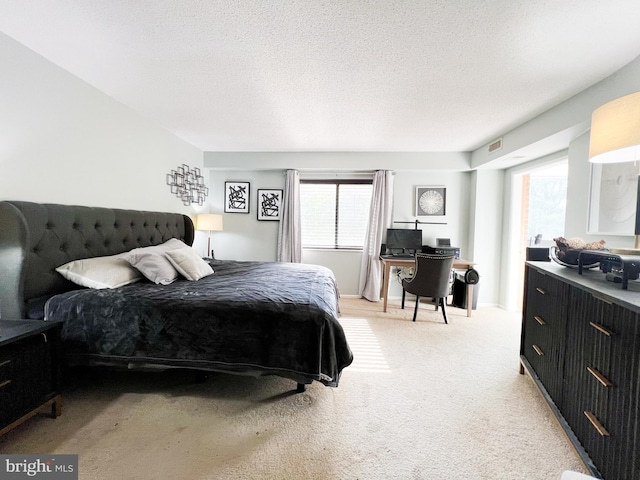 bedroom featuring light carpet, visible vents, and a textured ceiling