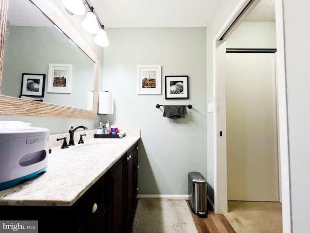 bathroom featuring a textured ceiling, wood-type flooring, and vanity