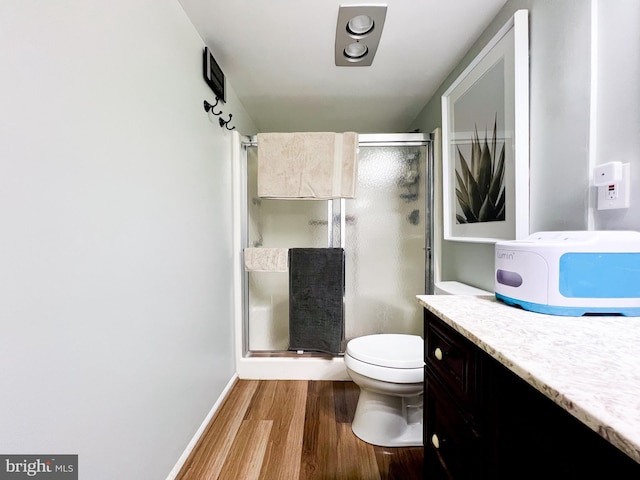 bathroom with vanity, toilet, hardwood / wood-style floors, and a shower with door