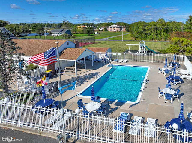 view of pool with a lawn, a playground, and a patio area