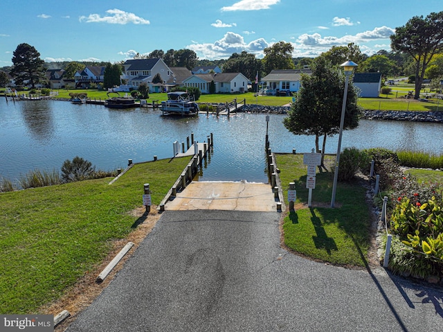 view of dock with a lawn and a water view