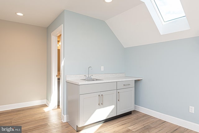 bathroom with wood-type flooring, vaulted ceiling, and vanity