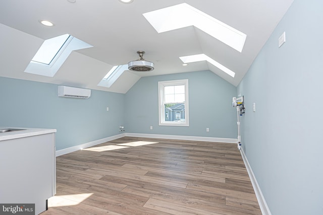 bonus room with hardwood / wood-style flooring, lofted ceiling with skylight, and a wall mounted AC