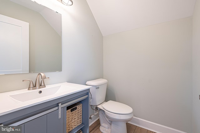 bathroom with vanity, lofted ceiling, hardwood / wood-style floors, and toilet