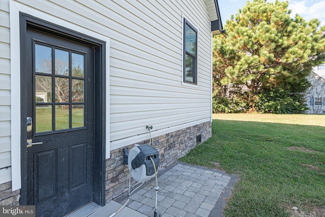 entrance to property featuring a lawn and a patio area