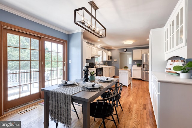 dining room with light wood-type flooring, crown molding, and sink