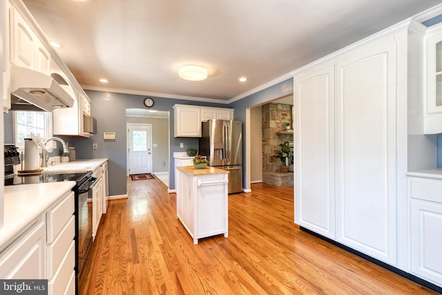 kitchen featuring light wood-type flooring, a healthy amount of sunlight, stainless steel fridge, and white cabinets