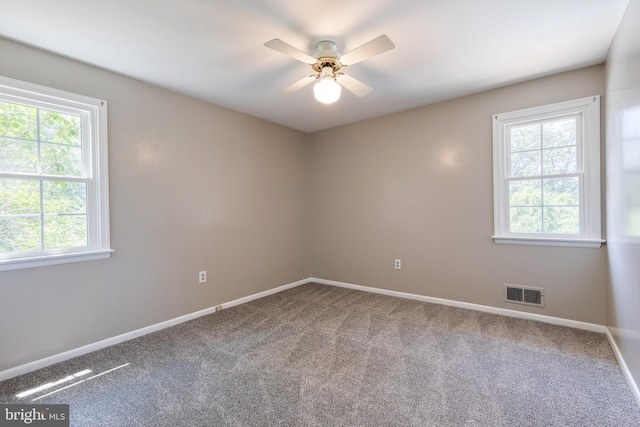 carpeted spare room featuring a healthy amount of sunlight and ceiling fan