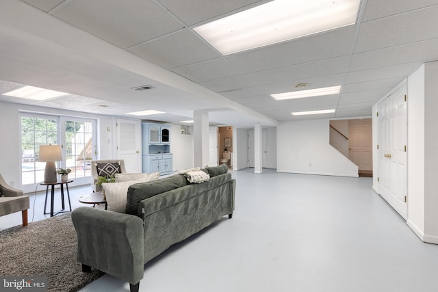 living room featuring concrete flooring and a paneled ceiling